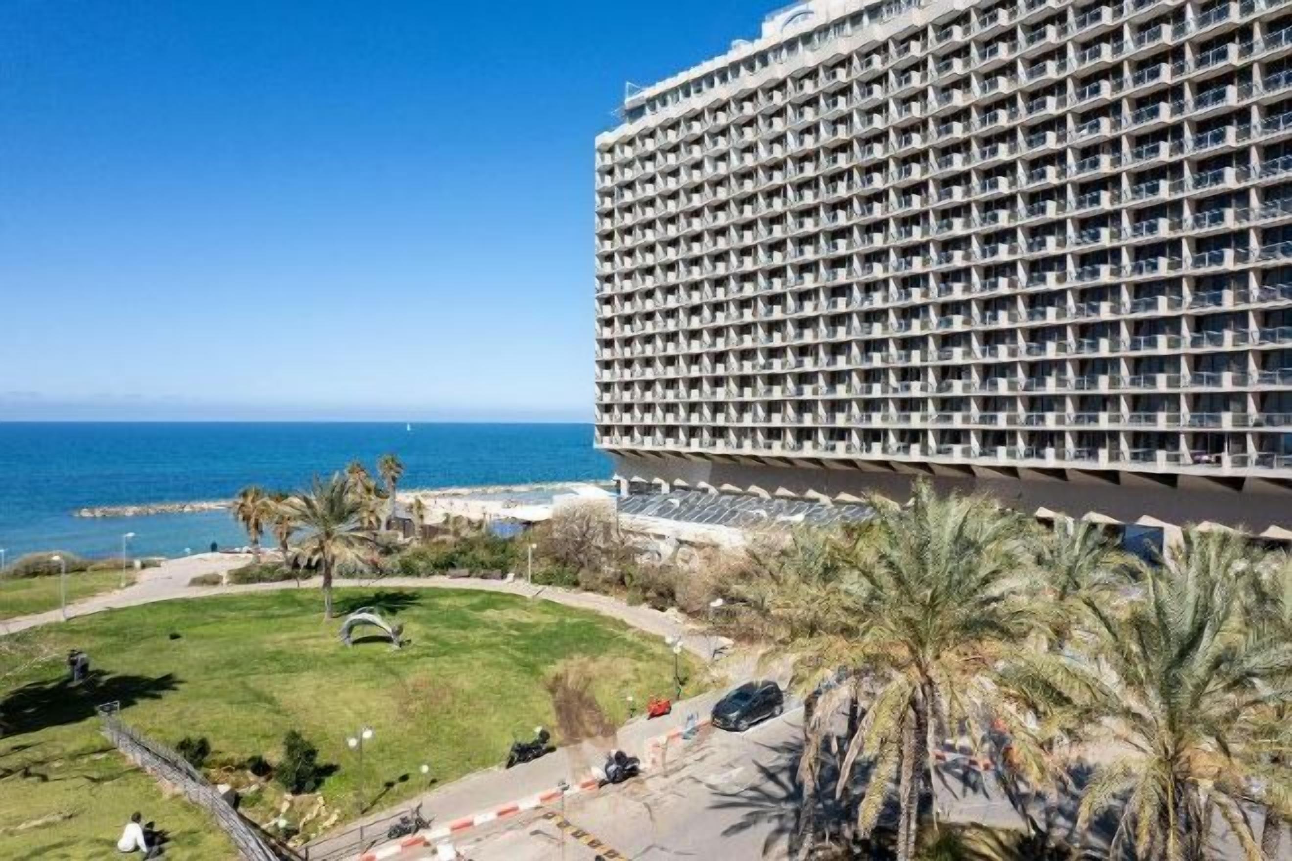 A large hotel with multiple balconies overlooking a beach and ocean.