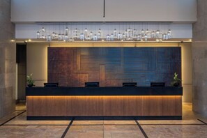 A reception desk with a modern design, featuring a wooden finish and a patterned back panel.