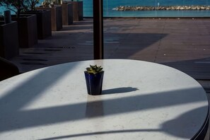 Ein runder Tisch mit einem Blumentopf, einer Holzterrasse und Blick aufs Meer.