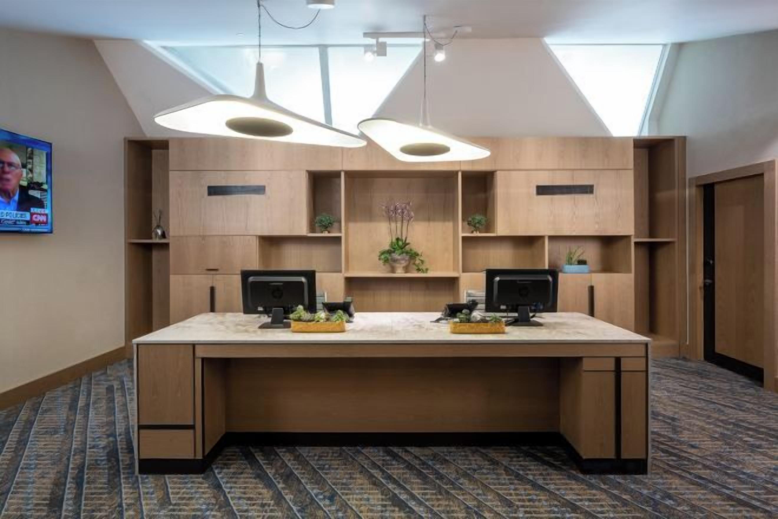 A conference room with a long table, two monitors, and a large window.
