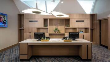 A conference room with a long table, two monitors, and a large window.