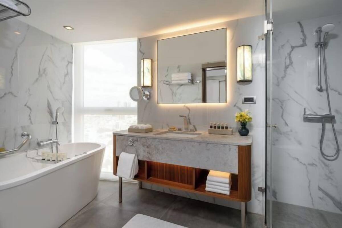 Een moderne badkamer met een vrijstaand bad, een wastafel met spiegel en een douchegedeelte.