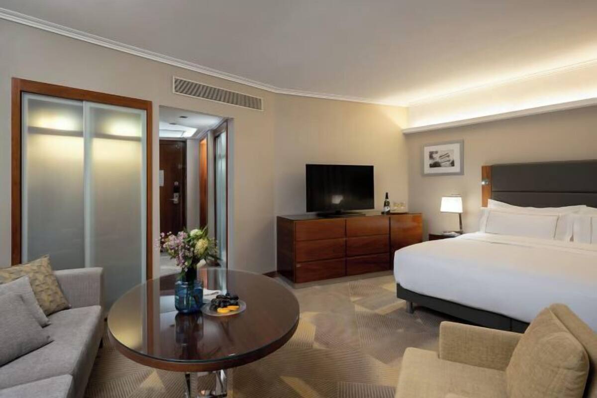 Een hotelkamer met een bed, een televisie, een bureau met een vaas en een bank.