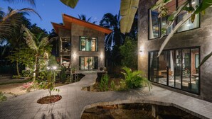 Une maison moderne dotée d’un chemin sinueux, de grandes fenêtres et d’un jardin bien entretenu.