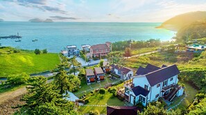 A coastal residential area with houses, a marina, and a view of the sea. - Hanulbora Pension (Yeosu)