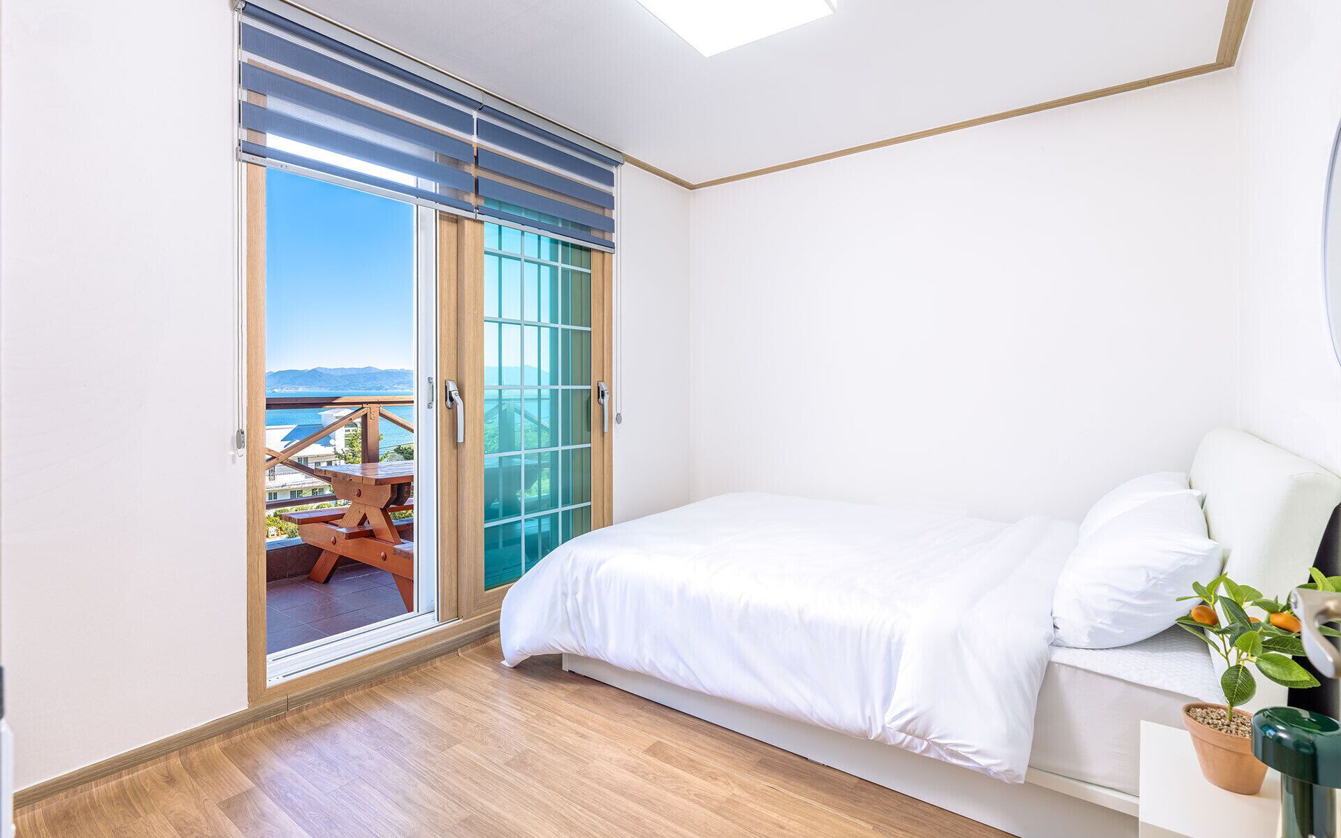 Un dormitorio con cama, una planta en maceta y vistas a un balcón con mesa y sillas.