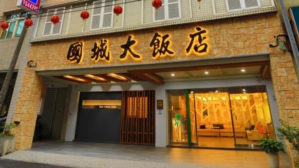 A hotel entrance with a stone facade, large glass doors, and a sign in a foreign script. - Guo Chen Hotel (Luodong)