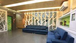 A modern lobby with a blue sofa, a decorative partition, and a reception desk. - Guo Chen Hotel (Luodong)