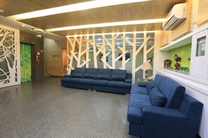 Um lobby moderno com um sofá azul, um painel decorativo e um balcão de recepção.