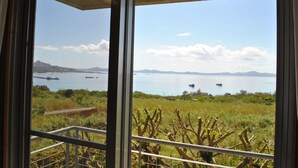 Un balcon offrant une vue sur une mer calme et des montagnes lointaines.