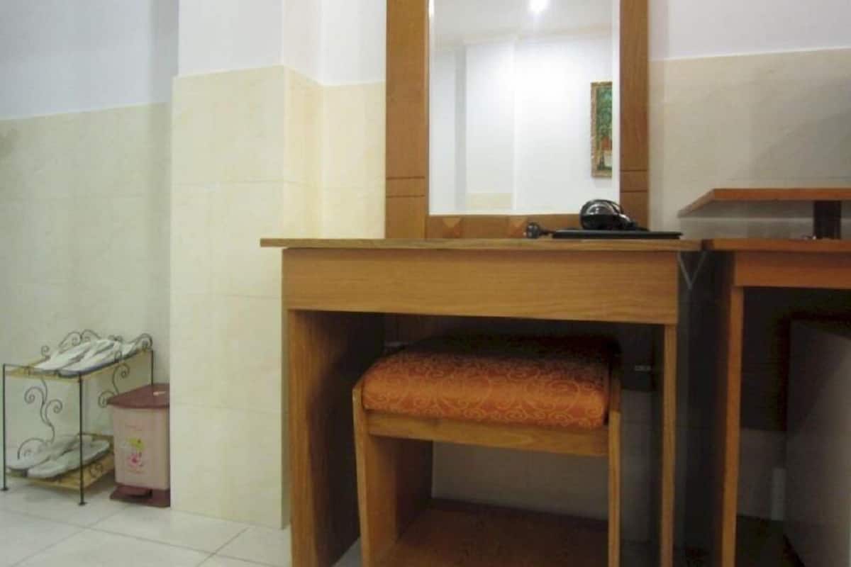 Un baño con tocador de madera, un espejo y un inodoro con cubierta decorativa.