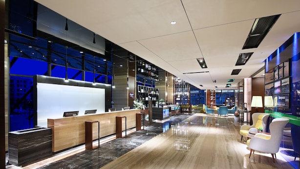 Un moderno vestíbulo de hotel con mostrador de recepción, zona de estar y bar.