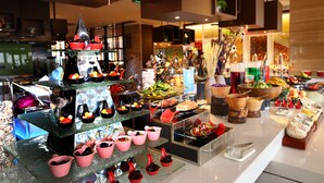 Un bufé con diversas opciones de comida y bebidas, entre ellas frutas, verduras y postres.