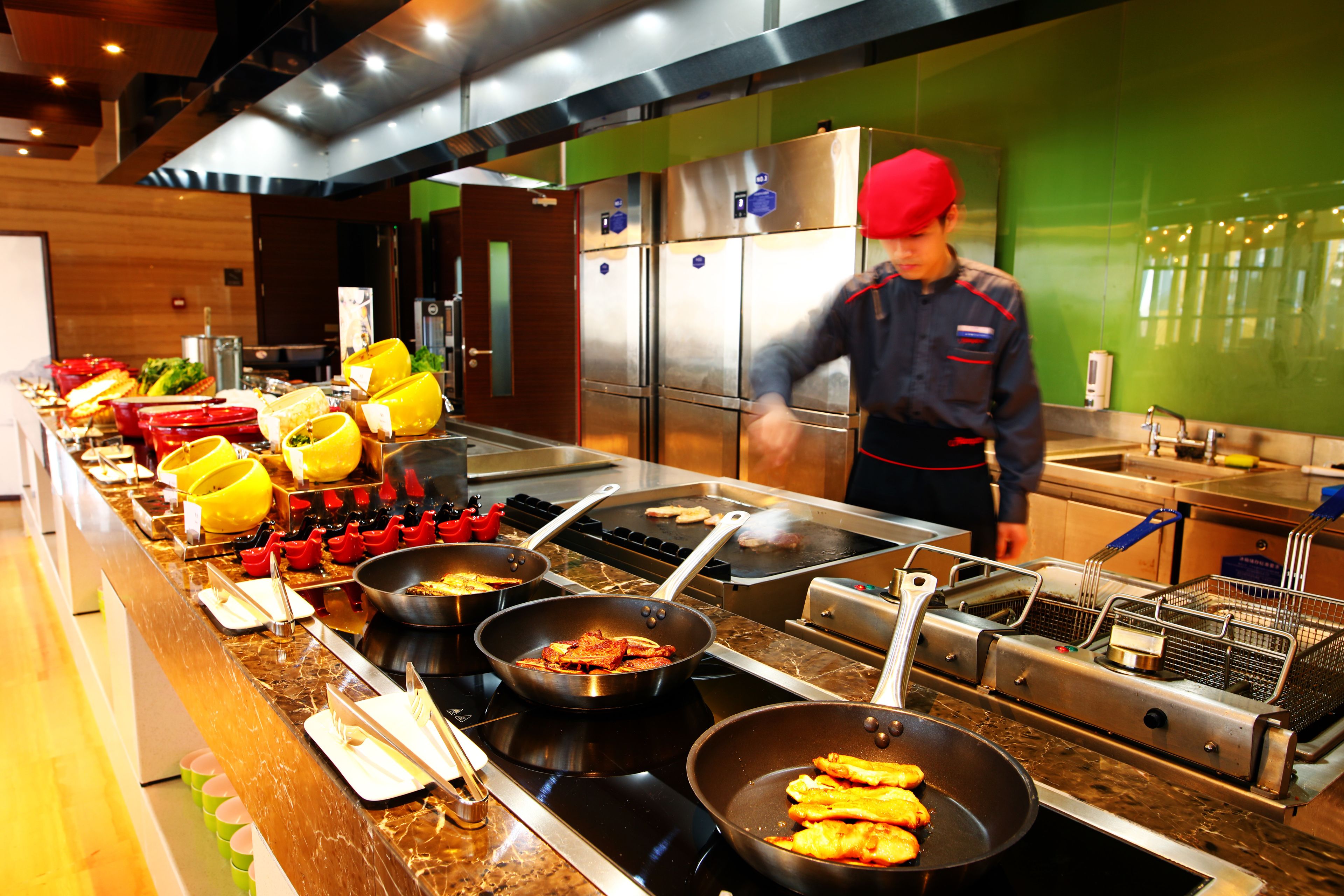 A buffet setup with various food items and cooking equipment.