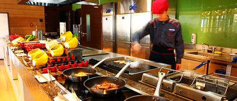 A buffet setup with various food items and cooking equipment.