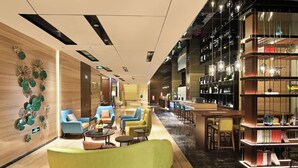 Un moderno vestíbulo de hotel con zonas de estar, un bar y una estantería.