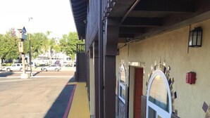 A covered outdoor area with a yellow tactile paving path, a fire lane, and a tiled wall with a window. - Hacienda Motel (Escondido)