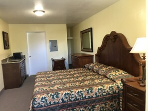 A bedroom with a bed, dresser, nightstand, and a mirror. - Hacienda Motel (Escondido)