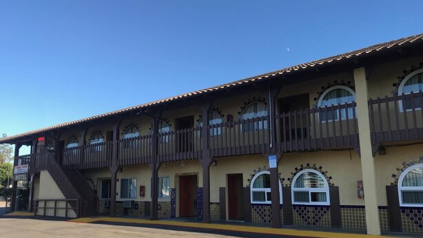 A motel with a two-story structure, multiple balconies, and a covered parking area. - Hacienda Motel (Escondido)