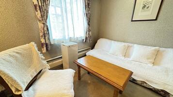 A room with a wooden chair, a wooden table, and a white sofa.