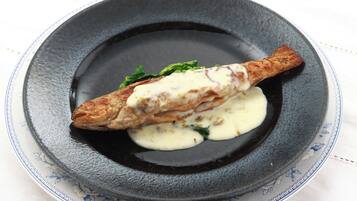 A plate with a fish, sauce, and greens.