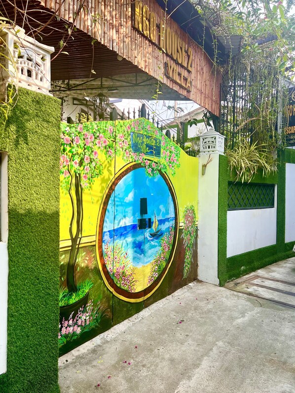 A building with a mural of a tree and flowers, a sign reading "No House 2 Me," and a bamboo structure above. - Ngo House 2 Villa (Da Nang)