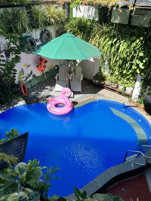 A swimming pool with a pink flamingo float, surrounded by potted plants and a mural. - Ngo House 2 Villa (Da Nang)