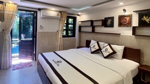 Habitación de hotel con una cama grande, una mesita de noche, cortinas en la ventana y una obra de arte en la pared.