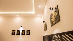 Un interior moderno con iluminación empotrada en el techo, un panel decorativo en la pared y un tapiz con motivos.