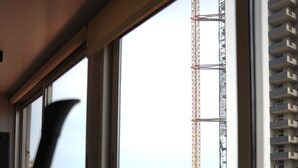 A view from a window with an exercise bike, overlooking a construction site and a tall building. - B Residence (Beirut)