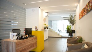 A modern reception area with a wooden desk, a yellow counter, and a seating area with sofas. - B Residence (Beirut)