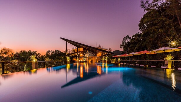 A tranquil pool area at dusk with a covered seating area and umbrellas. - Marina Sands Resort (Ko Chang)