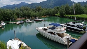 A marina with several boats docked, surrounded by lush greenery and mountains in the background. - Marina Sands Resort (Ko Chang)