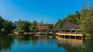 A lakeside hotel with a dock extending into the water, surrounded by lush greenery and a mountain in the background. - Marina Sands Resort (Ko Chang)