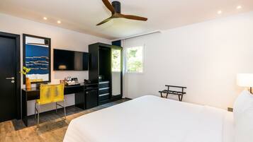 Una habitación de hotel con cama, escritorio, silla y ventilador de techo.