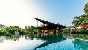 A clear pool with a modern building in the background, surrounded by lush greenery. - Marina Sands Resort (Ko Chang)