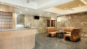 A reception area with a curved counter, seating, and a ceiling fan. - Sakthi Residency (Kumbakonam)