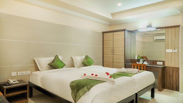 A hotel room with a large bed, a desk, and a wardrobe. - Sakthi Residency (Kumbakonam)