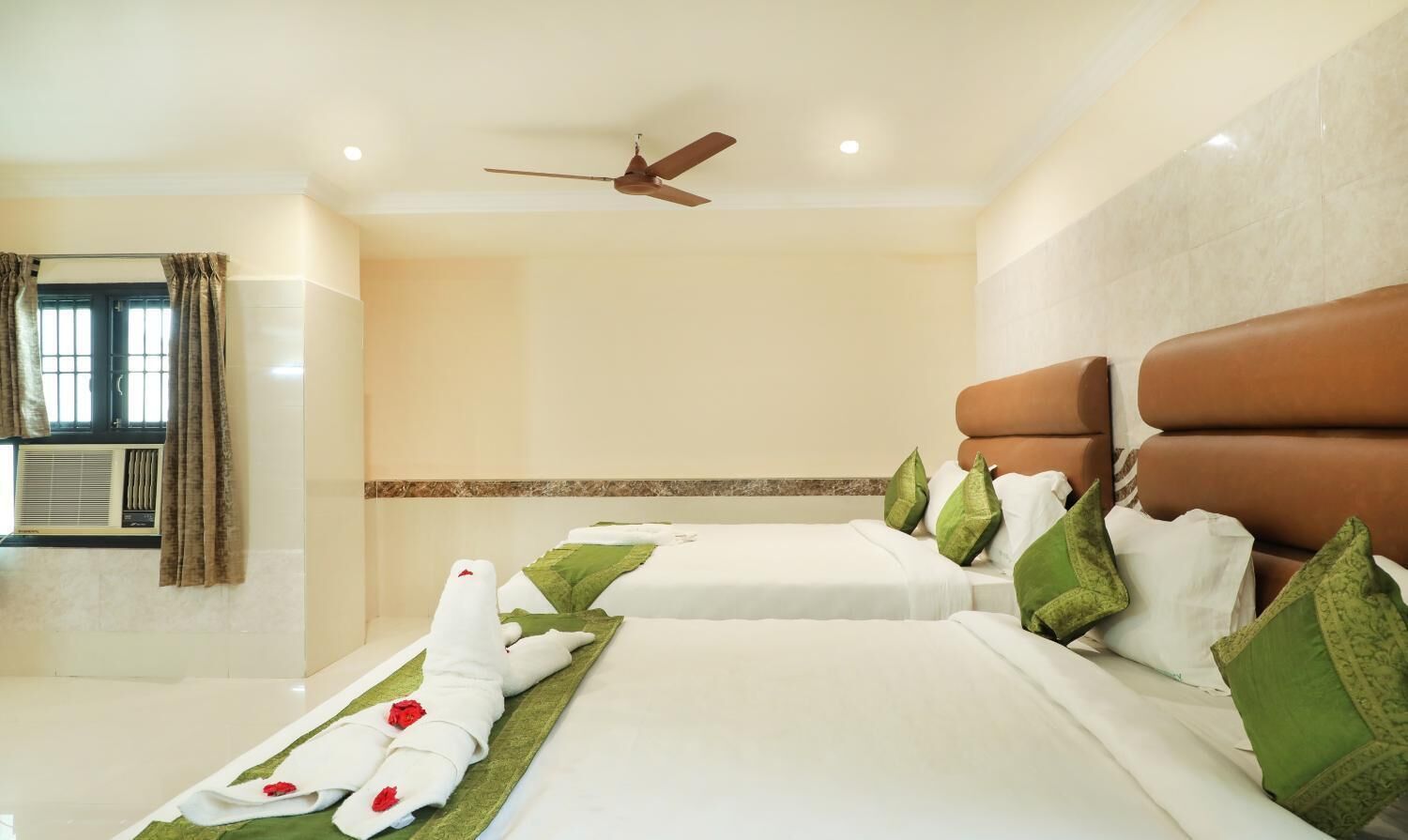 A hotel room with two beds, a ceiling fan, and a window with curtains.