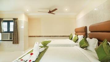 A hotel room with two beds, a ceiling fan, and a window with curtains.