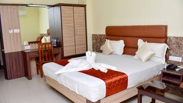 A hotel room with a bed, a desk, a chair, and a wardrobe.