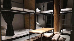 A bunk bed room with a wooden table and a fur rug. - Homy Seafront Hostel (Kota Kinabalu)