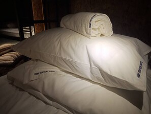A bed with white pillows and a rolled-up towel, each labeled "HOMY SEAFRONT HOSTEL". - Homy Seafront Hostel (Kota Kinabalu)