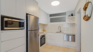 Uma cozinha moderna com armários brancos, eletrodomésticos de aço inoxidável e uma pequena janela sobre a pia.