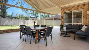 Un patio couvert avec un mur en briques, une table à manger avec des chaises et un canapé.