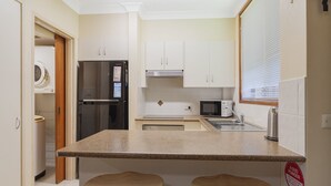 Eine kleine Küche mit Kühlschrank, Mikrowelle und Spüle.