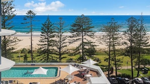 Un resort con piscina, vista al mar y pinos.