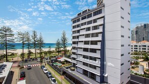 A modern hotel with multiple floors, a parking area, and a view of the beach and ocean.