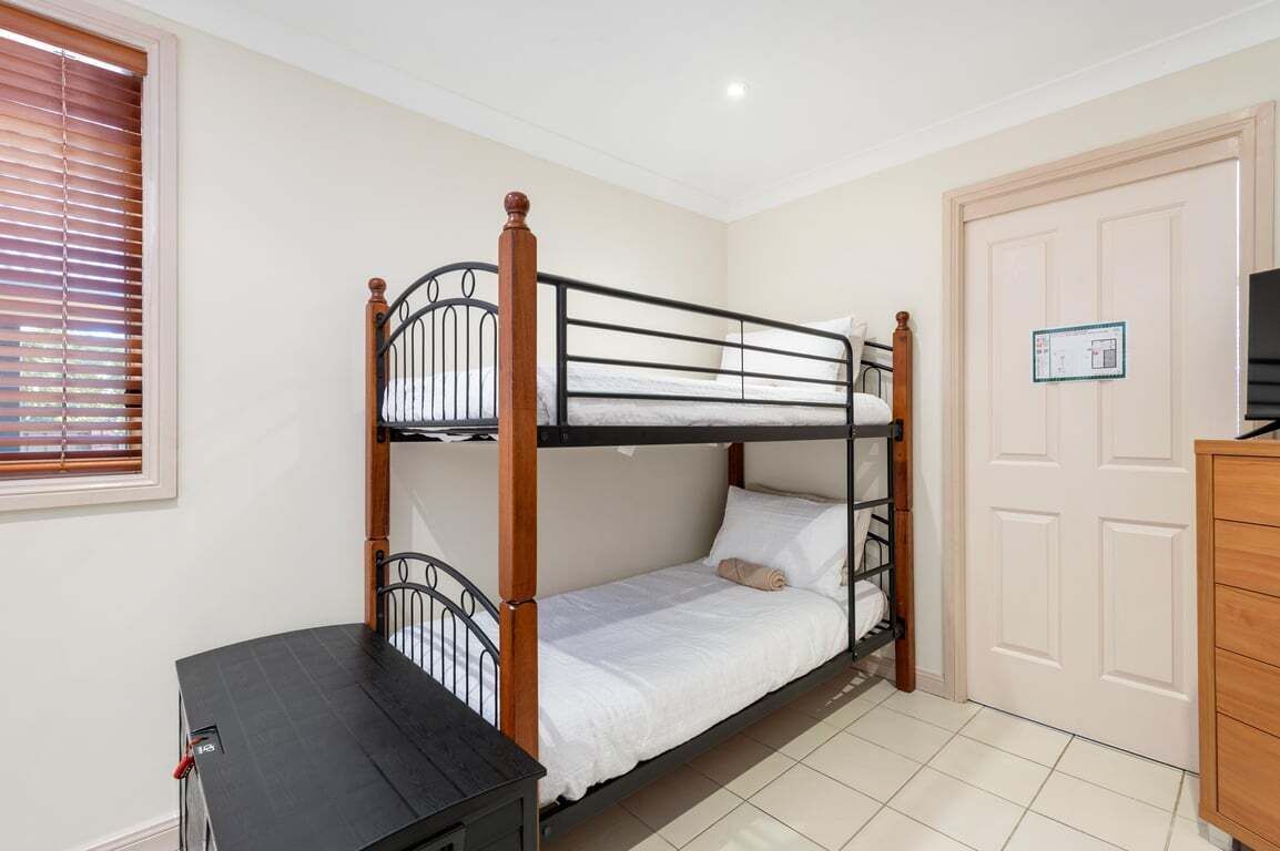 A bunk bed room with a wooden headboard, a small table, and a door with a sign.