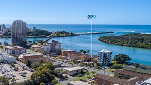 Un paisaje urbano costero con una mezcla de edificios altos y bajos, un puerto deportivo y una vista despejada del océano.